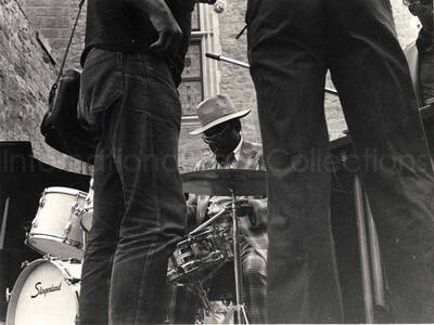 7 x 9 1/2 inch photograph. Lionel Hampton performing on vibraphone accompanied by unidentified musicians [in Marseille, France?]. Handwritten on the back of the photograph: Salon - France; before the concert