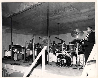 8 x 10 inch photograph. Lionel Hampton on drums with band, among which is guitarist Billy Mackel. Stamped on the back of the photograph: USS Lake Champlain CVS-39