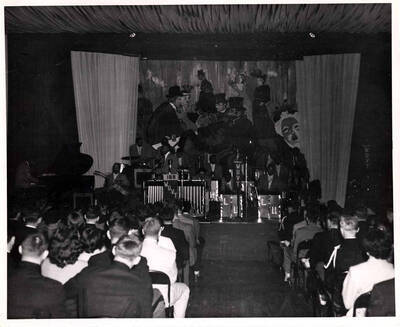 8 x 10 inch photograph. Lionel Hampton on vibraphone with band. Seen in front of the microphone is a banner of the IBS WUVT [Virginia Tech]