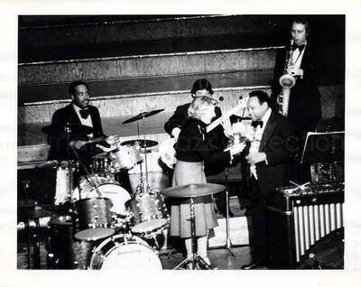 8 x 10 inch photograph. Lionel Hampton receiving flowers from an unidentified woman on stage with band