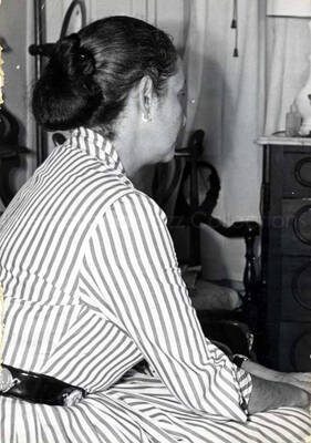 5 x 3 1/2 inch photograph. Unidentified woman sitting with her back to the camera. This photograph has been ripped off