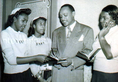 5 x 7 inch photograph. Lionel Hampton signing autographs. The front of the sweater of two of the young women reads: Hamp