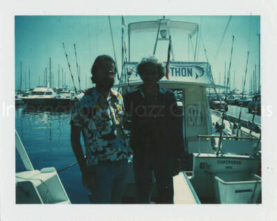 3 1/2 x 4 1/4 inch photograph. Jean Claude Forestier with Bill Titone standing on a deck. Observable in the background is a boat with the French words: thon, coryphene, Nice. [France?]