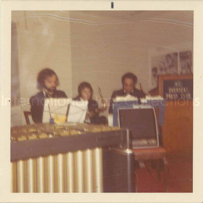 3 1/2 x 3 1/2 inch photograph. Lionel Hampton and band at the Overseas Press Club of America. A banner on the wall reads: Welcome Lionel Hampton, America's Good Will Ambassador of Jazz
