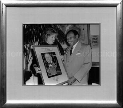 13 3/4 x 15 3/4 inch frame holding a black and white photograph. Has a label on the back from the BMI Archives. Lionel Hampton receiving a plaque from BMI President Frances W. Preston at the Tavern on the Green, New York