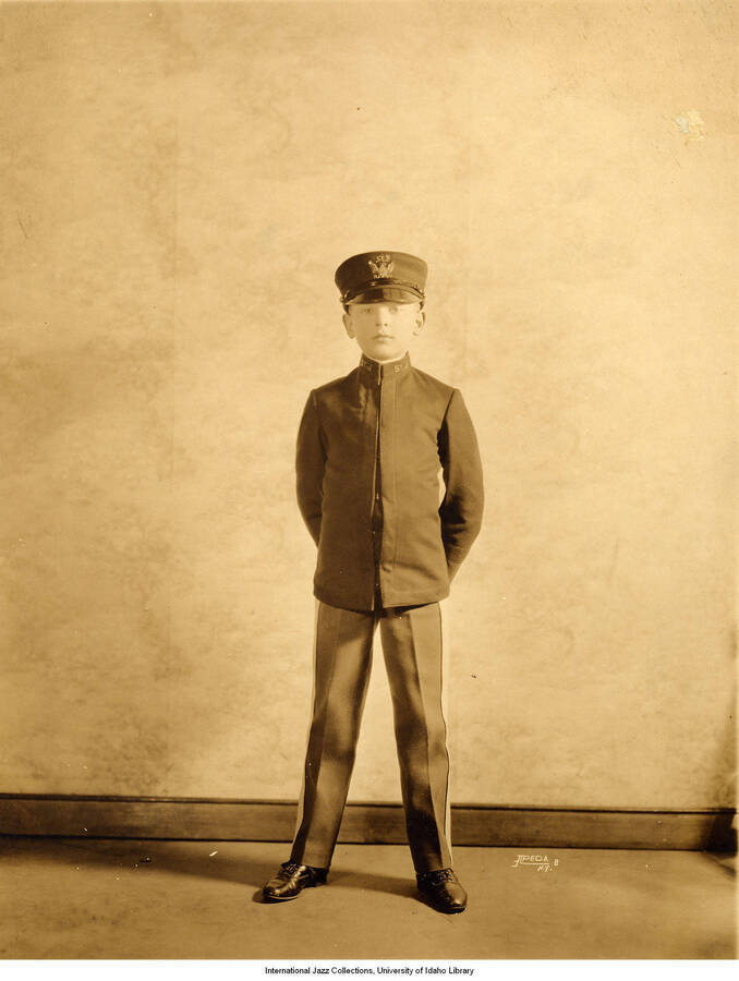 Photograph of a young child dressed in a dark uniform jacket and hat.