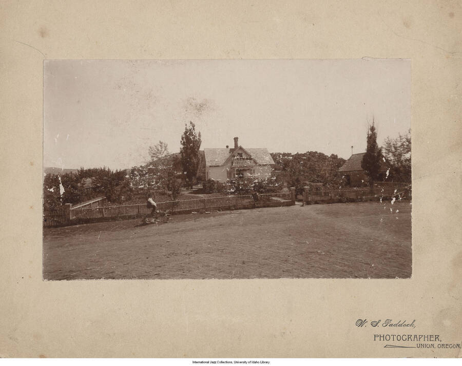 Photograph of Lee Morse's house surrounded by a fence.