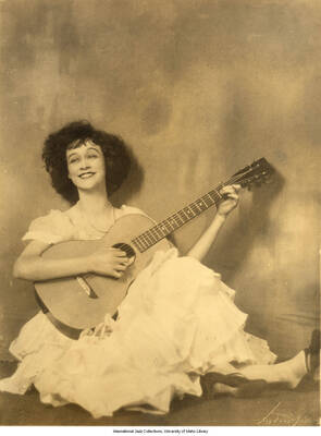 Black and white photograph of Lee Morse sitting and holding a guitar.