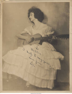 Black and white photograph of Lee Morse holding a guitar. Inscription: For Bobbie "I hate to say goodby" Love from Lee