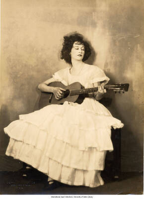 Black and white photograph of Lee Morse sitting and holding a guitar.