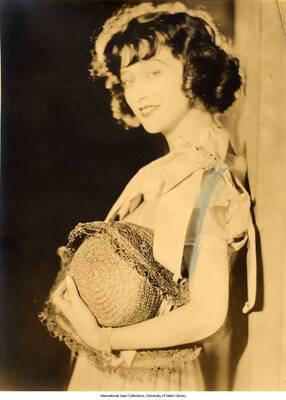 Black and white photograph of Lee Morse holding a straw hat. 
