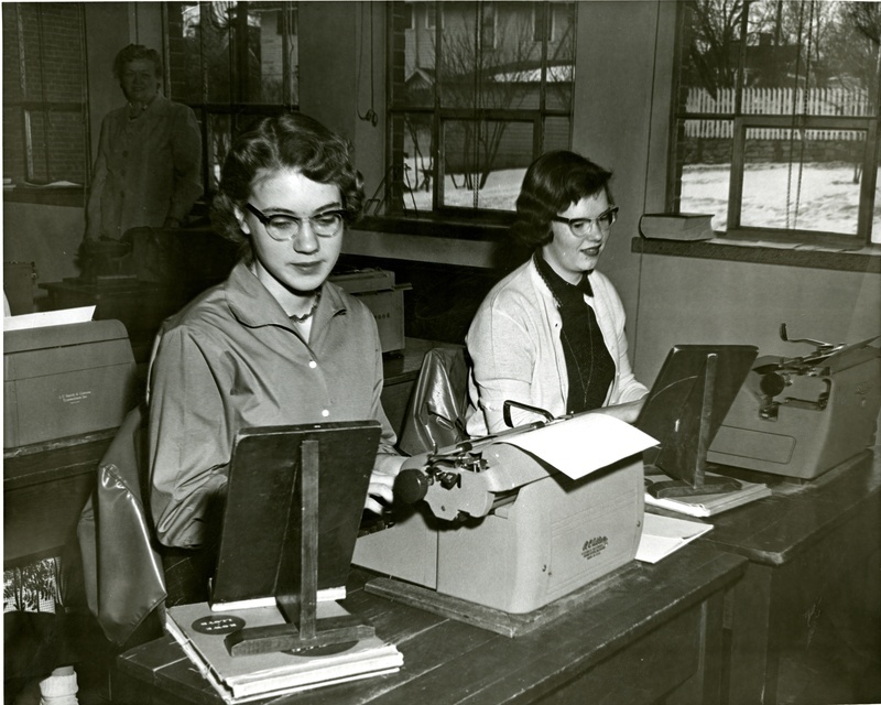 Two girls working at typewriters in MHS classroom
