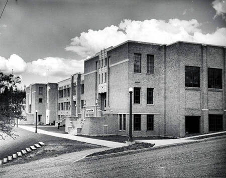 Image of brick MHS 1960, art deco architecture visible, with lampposts and sidewalks visible
