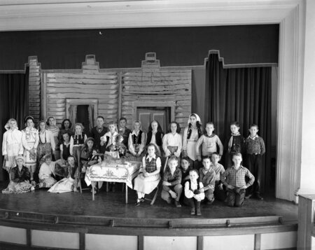 Students standing in costumes on a classroom stage
