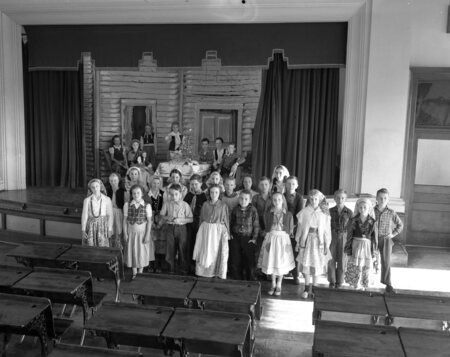 Students standing in costumes on a classroom stage