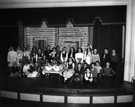 Students standing in costumes on a classroom stage