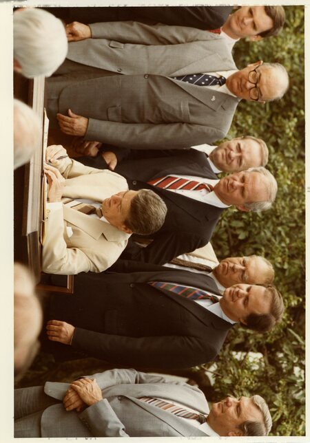 Photograph of Senator James A. McClure and others observing President Ronald Reagan as he signs four Wilderness bills in the White House Rose Garden.