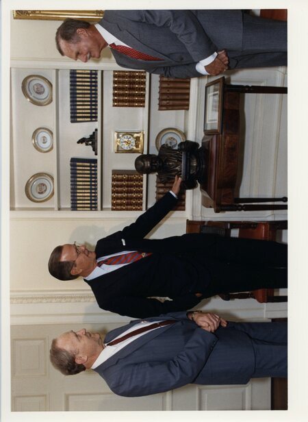 Photograph of Senator James A. McClure, President George H. W. Bush, and John "Jack" Hemingway, son of writer Ernest Hemingway, standing near a bust of Ernest Hemingway in the White House.