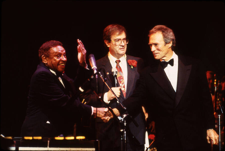35mm color slide. Clint Eastwood shakes Lionel Hampton's hand after receiving the Lionel Hampton Jazz Hall of Fame award. Also on stage is Lynn "Doc" Skinner.