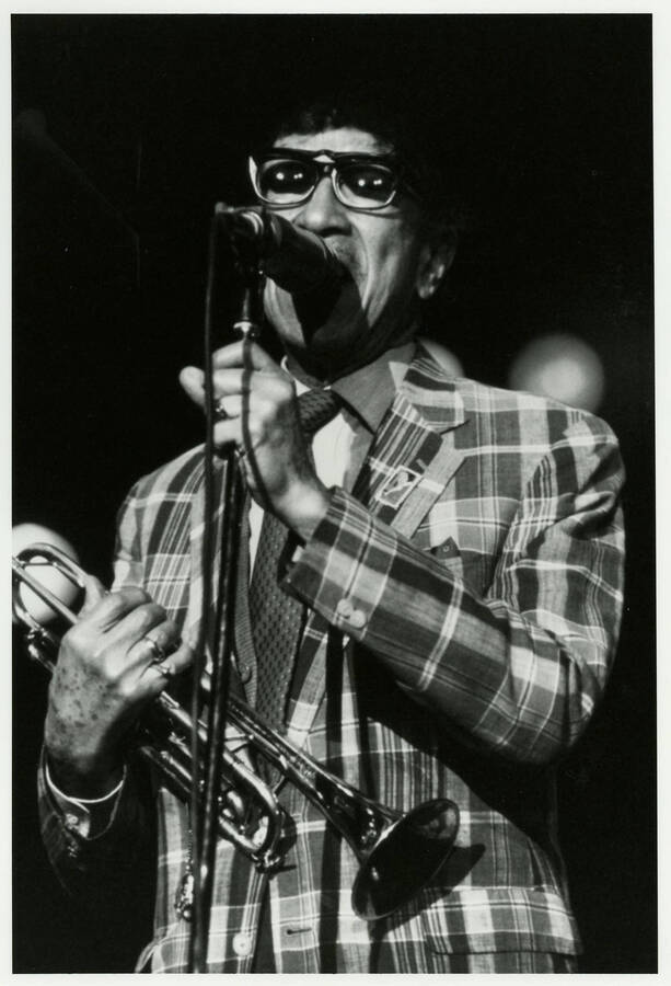 8" x 10" black and white photograph. Doc Cheatham speaks into a microphone while holding his trumpet at the 1989 Lionel Hampton-Chevron Jazz Festival.