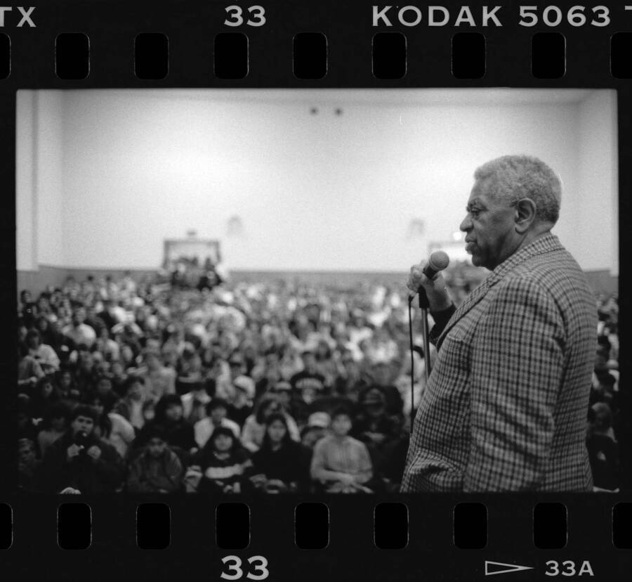 1.5" x 1" black and white print. One of thirty images found on a contact sheet. Dizzy Gillespie speaking into microphone to audience during his jazz clinic.