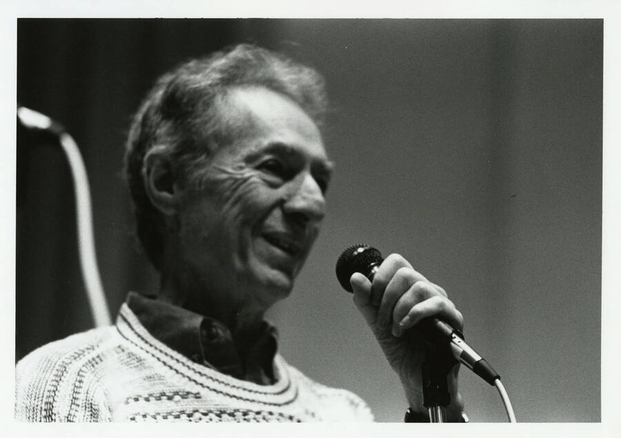 7" x 5" black and white photograph. Leonard Feather speaks into a microphone, possibly at a clinic.
