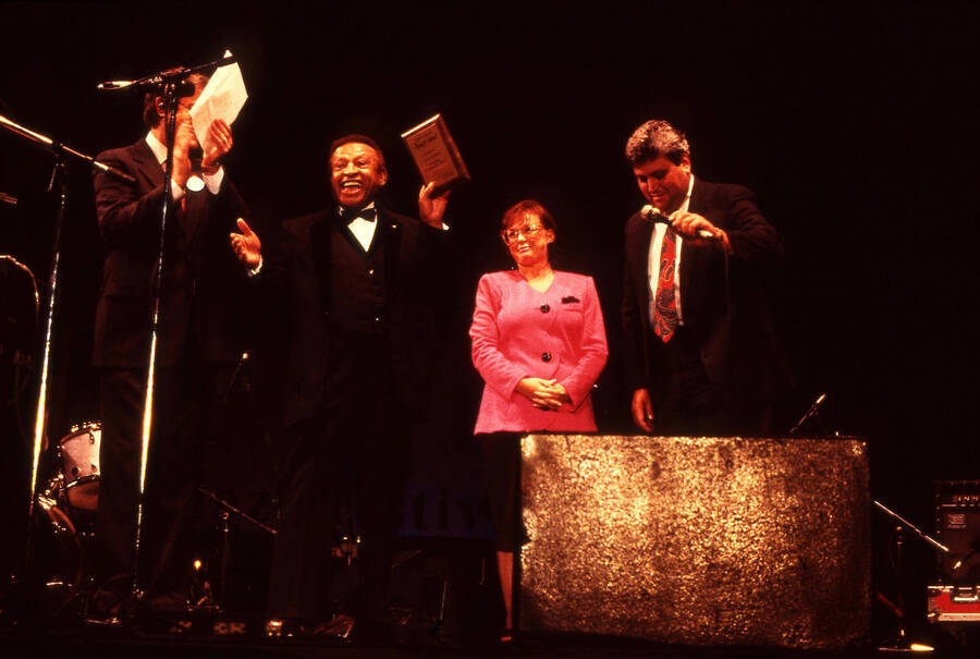 35 mm color slide. Lionel Hampton and Lynn "Doc" Skinner present two unidentified individuals a plaque on stage at the Pepsi International World Jazz Night at the 1992 Lionel Hampton-Chevron Jazz Festival.