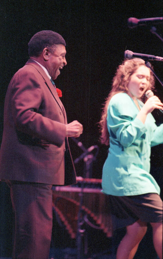 35mm color negative. A student vocalist performs at the 1991 Lionel Hampton-Chevron Jazz Festival evening concert while Lionel Hampton stands to the side.