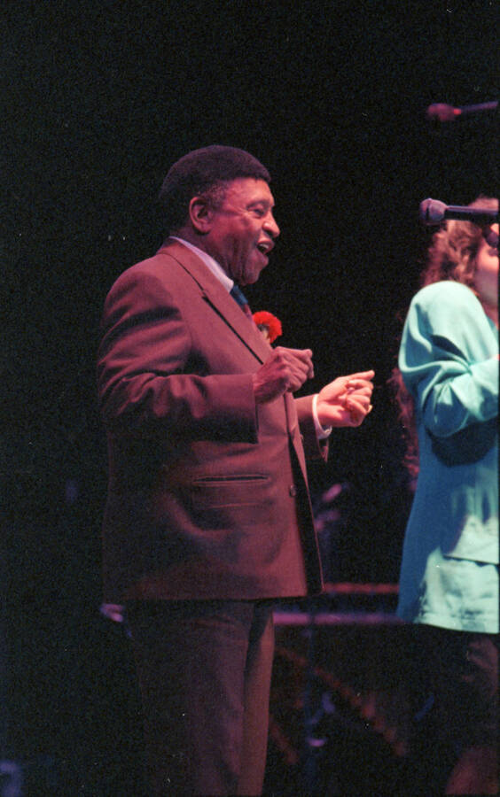 35mm color negative. A student vocalist performs at the 1991 Lionel Hampton-Chevron Jazz Festival evening concert while Lionel Hampton stands to the side.