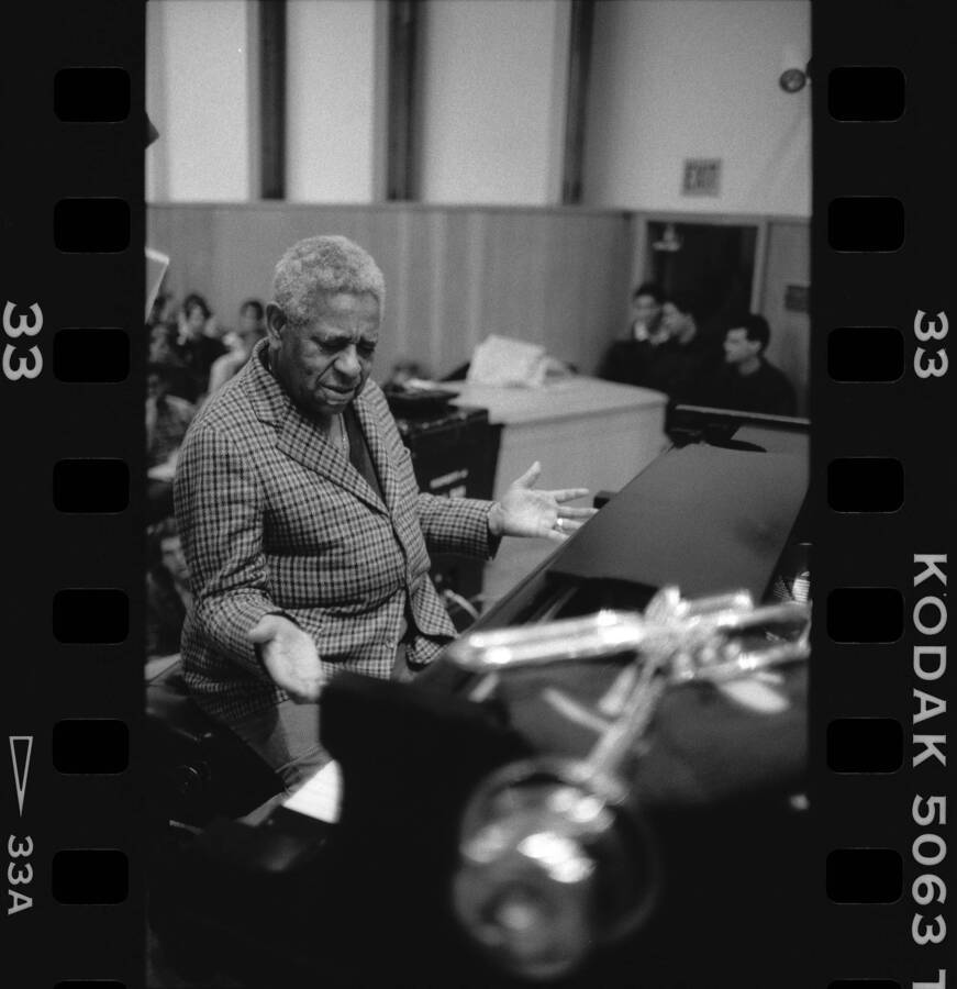 1" x 1.5" black and white print. One of thirty images found on a contact sheet. Dizzy Gillespie sitting at piano during his jazz clinic.