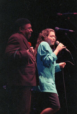35mm color negative. A student vocalist performs at the 1991 Lionel Hampton-Chevron Jazz Festival evening concert while Lionel Hampton stands to the side.