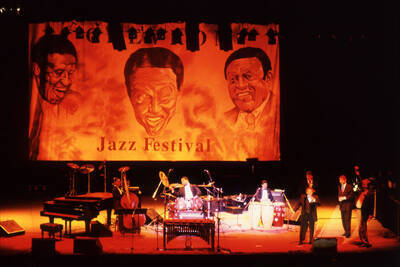 35 mm color slide. Lionel Hampton speaks into a microphone with Leon Dorsey, Wally "Gator" Watson, Gabriel Machado, Lembit Saarsalu, Leonid Vintskevich, and Lynn "Doc" Skinner on stage at the Pepsi International World Jazz Night  at the 1992 Lionel Hampton-Chevron Jazz Festival.