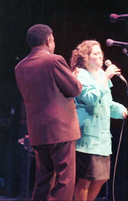 35mm color negative. A student vocalist performs at the 1991 Lionel Hampton-Chevron Jazz Festival evening concert while Lionel Hampton stands to the side.