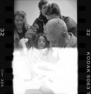 1" x 1.5" black and white print. One of thirty images found on a contact sheet. Dizzy Gillespie signing jazz festival programs for students.