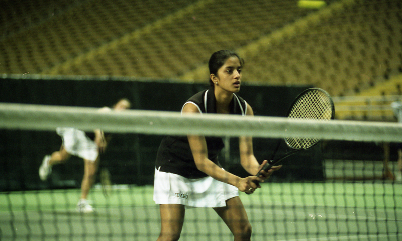 Color photograph of a tennis player holding a racquet, empty stands behind her.