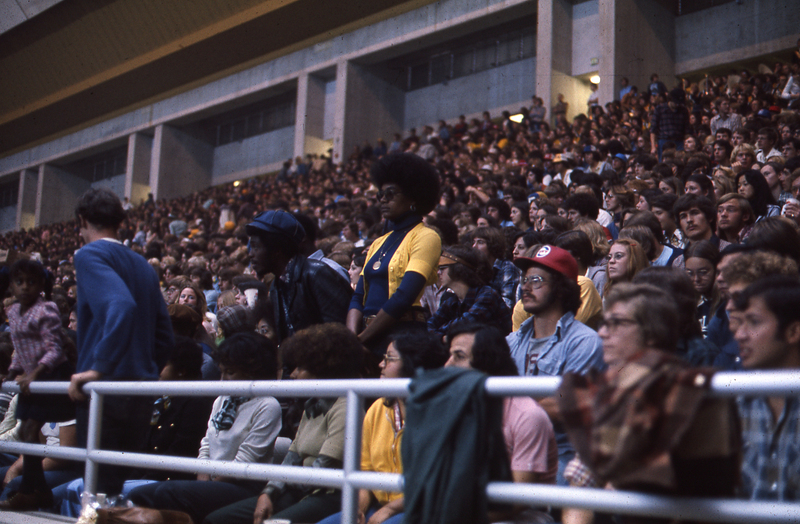 Color photograph of spectators sitting in stands.