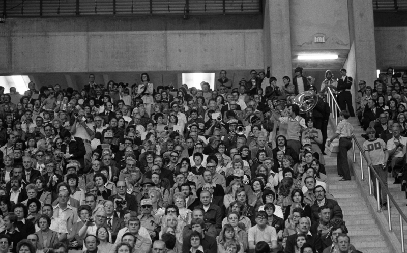 Black and white photographs of spectators sitting in stands.