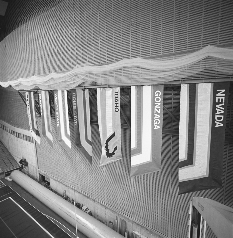 Black and white photograph of a large banner reading "IDAHO" and depicting stylized images of male and female heads in profile.