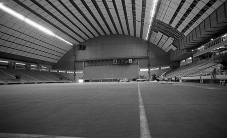 Black and white photograph of the interior of an enclosed football stadium.
