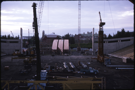 Color photograph of a construction site. Construction equipment and wooden arches sit on the ground.