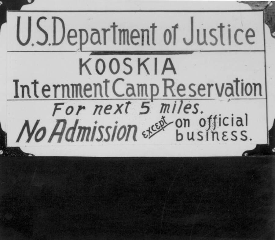 Image of sign at Kooskia Internment Camp reading, "U.S. Department of Justice Kooskia Internment Camp Reservation for next 5 miles. No Admission except on official business." Photo taken from 12-3/4 x 15-1/4 Photograph album of the Kooskia Japanese Internment Camp.