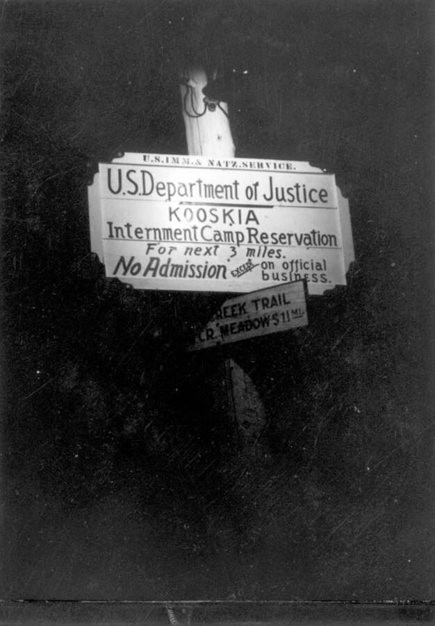 Image of sign at Kooskia Internment Camp reading, "U.S. Department of Justice Kooskia Internment Camp Reservation for next 3 miles. No admission except on official business". Photo taken from 12-3/4 x 15-1/4 Photograph album of the Kooskia Japanese Internment Camp.