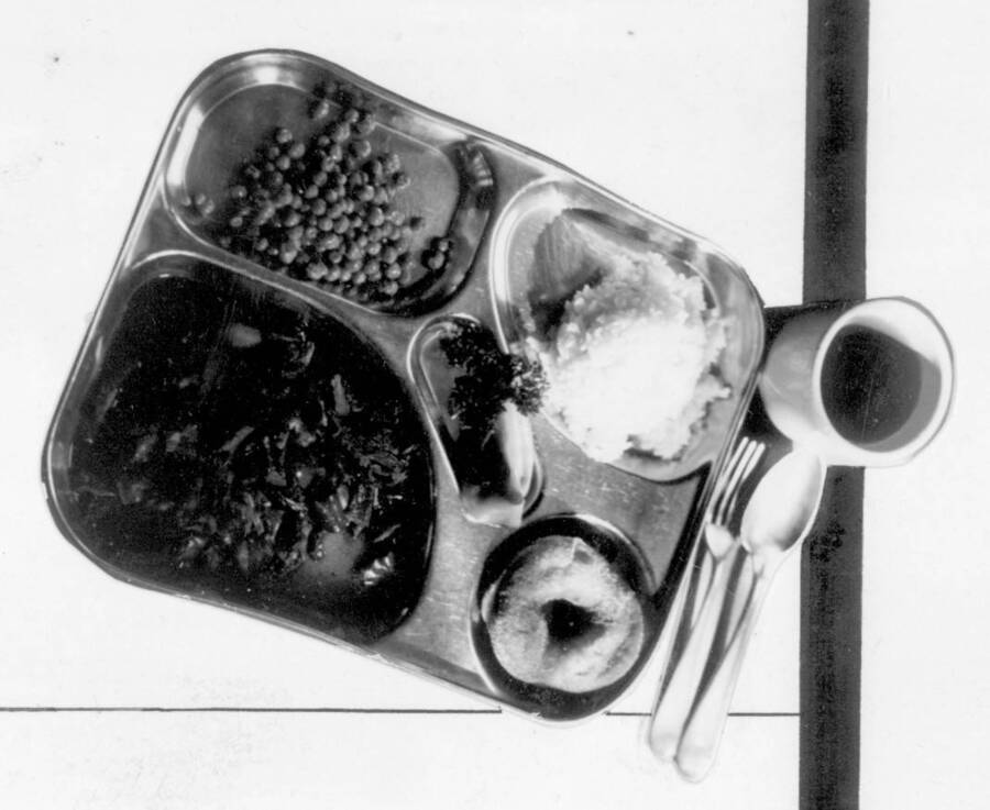 Image of food tray with food, drink and silverware at Kooskia Internment Camp.. Photo taken from 12-3/4 x 15-1/4 Photograph album of the Kooskia Japanese Internment Camp.