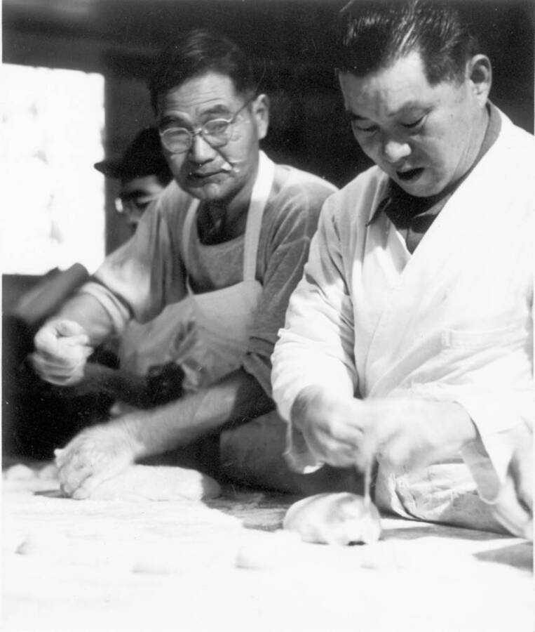 Interior shot of men working with dough at Kooskia Internment Camp. Photo taken from 12-3/4 x 15-1/4 Photograph album of the Kooskia Japanese Internment Camp.