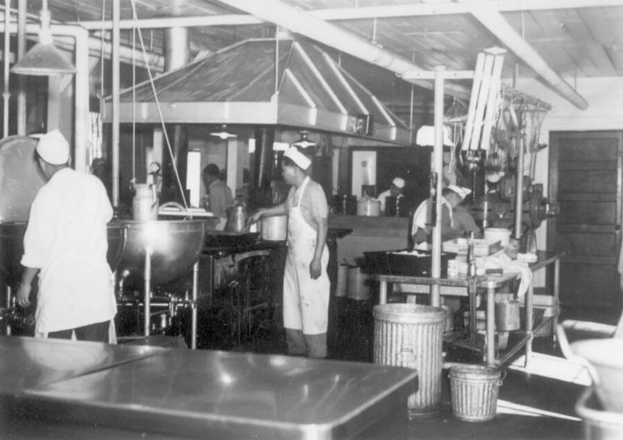 Interior image of men working in kitchen at Kooskia Internment Camp. Photo taken from 12-3/4 x 15-1/4 Photograph album of the Kooskia Japanese Internment Camp.