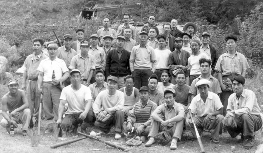 Image of group of men  with baseball equipment at Kooskia Internment Camp. Photo taken from 12-3/4 x 15-1/4 Photograph album of the Kooskia Japanese Internment Camp.