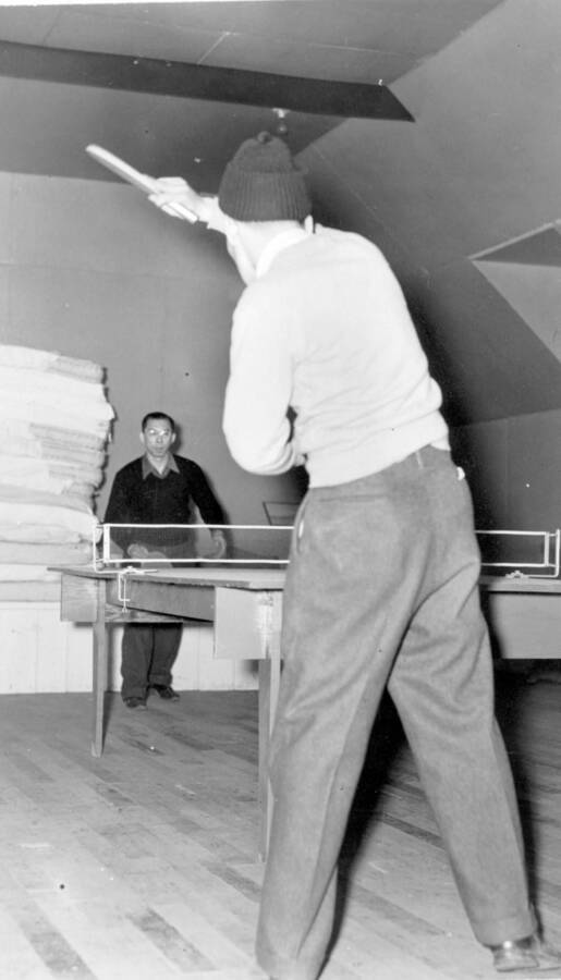 Interior image of two men playing a game of table tennis at Kooskia Internment Camp. Photo taken from 12-3/4 x 15-1/4 Photograph album of the Kooskia Japanese Internment Camp.