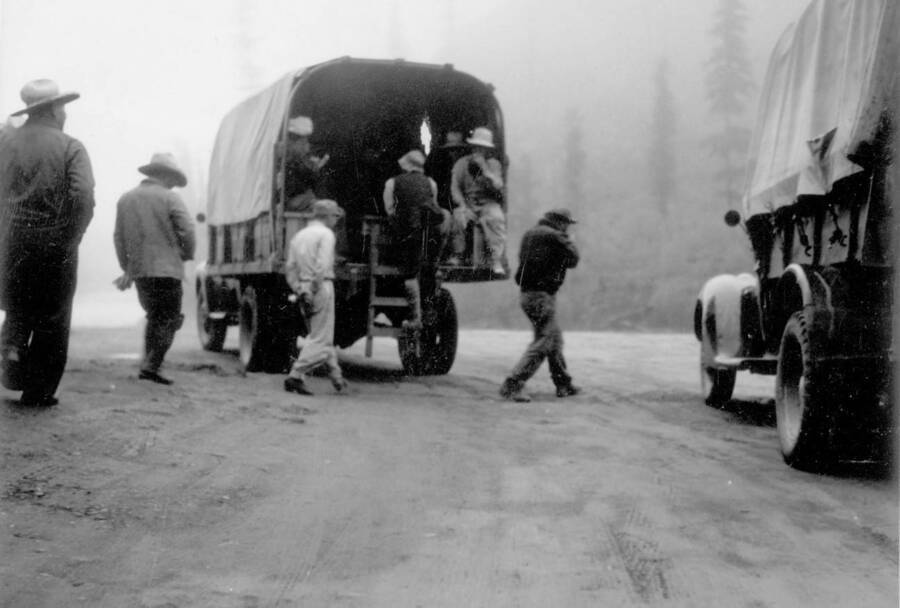 Image of men behind and inside a truck at Kooskia Internment Camp. Workers rode in trucks to the construction site daily to begin working on the day's project. Photo taken from 12-3/4 x 15-1/4 Photograph album of the Kooskia Japanese Internment Camp.