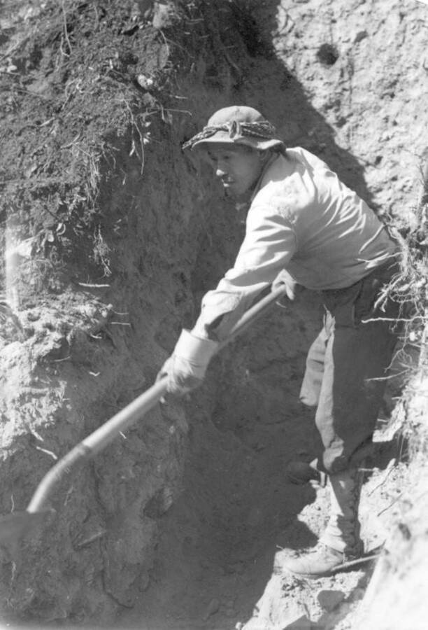 Image of man working in trench with shovel at Kooskia Internment Camp. Photo taken from 12-3/4 x 15-1/4 Photograph album of the Kooskia Japanese Internment Camp.