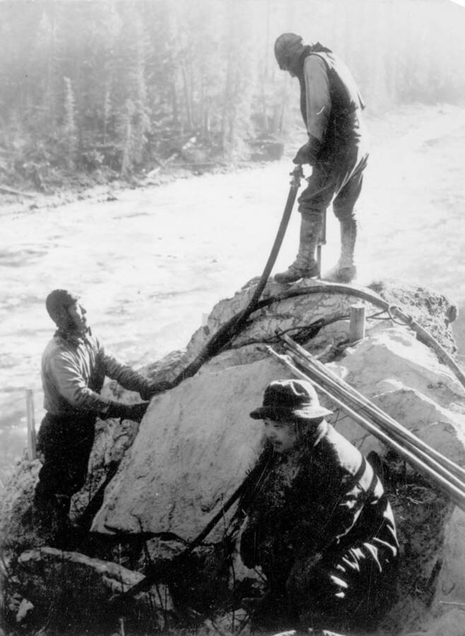 Image of three men from Kooskia Internment Camp working with construction equipment. Photo taken from 12-3/4 x 15-1/4 Photograph album of the Kooskia Japanese Internment Camp.